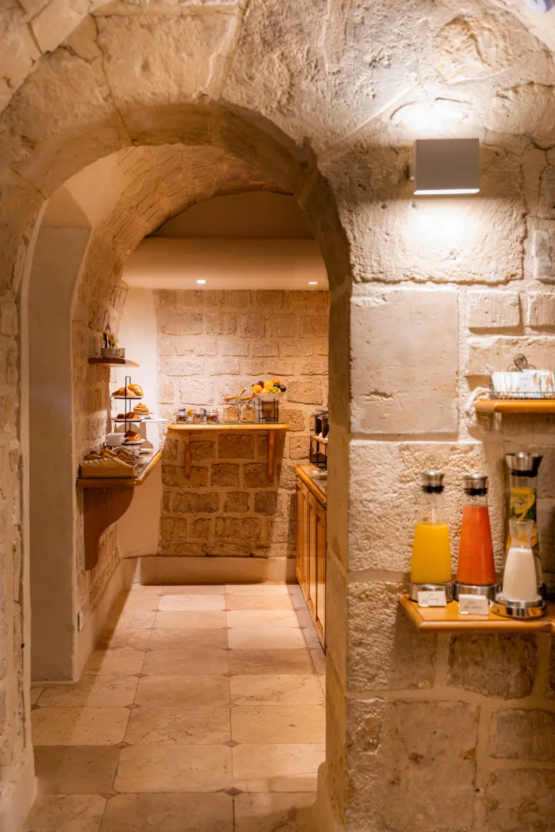 Arche en pierre voütee donnant sur la salle de petit-dejeuner de l'hotel Cordelia avec buffets et etageres